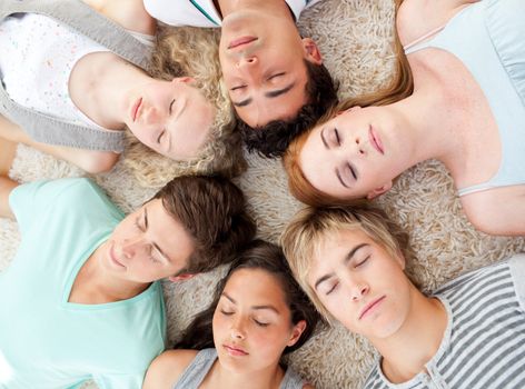 High angle of teenagers with their heads together sleeping on the ground at home