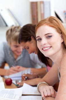 Smiling teen girl studying in the library with her friends. Concept of education