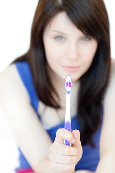 Charming woman holding a toothbrush against a white background