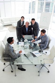 Business people working at a computer in a meeting smiling at the camera