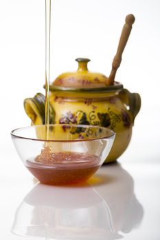 Honey pouring to glass mug on white background