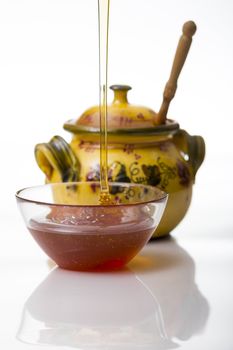 Honey pouring to glass mug on white background