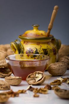 Transparent mug full of honey, honey jar and walnut