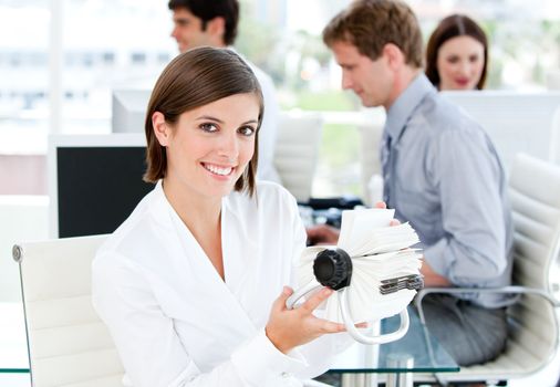 Smiling businesswoman looking for a contact in her white cards  in the office