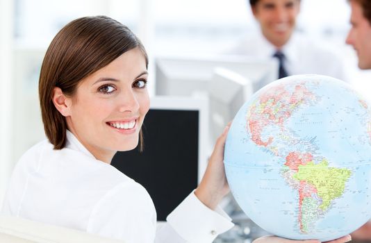 Smilling businesswoman holding a globe in the office 