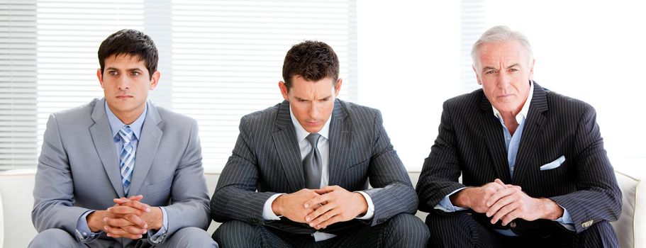 Three charismatic businessmen sitting on a sofa in a waiting room