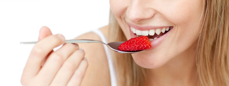 Close-up of a smiling woman eating a strawberry against a white background