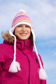 Smiling young woman wearing knitted winter cap and winter jacket