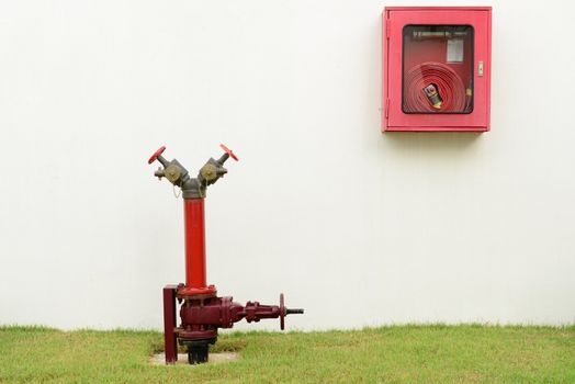 The red fire hydrant and fire hose next to the building