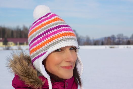 Smiling young woman wearing knitted winter cap with natural winter background