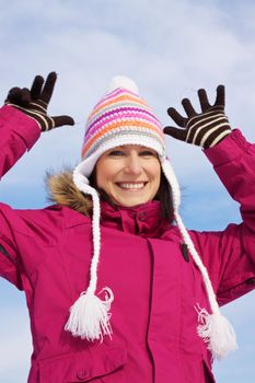 Smiling young woman wearing knitted winter cap and gloves