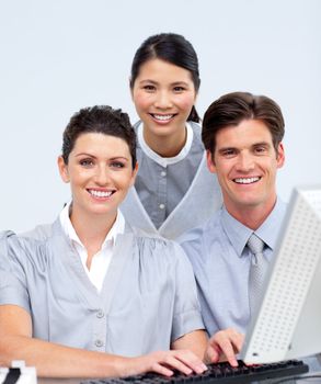 Portrait of three colleagues working at a computer in a company
