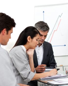 Concentrated business partners studying a document in a meeting