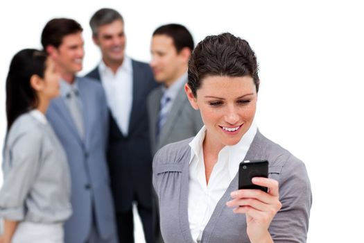 Attractive businesswoman looking at her cellphone in front of her team against a white background