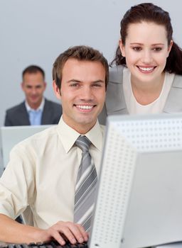 Charming businesswoman helping her colleague at a computer 