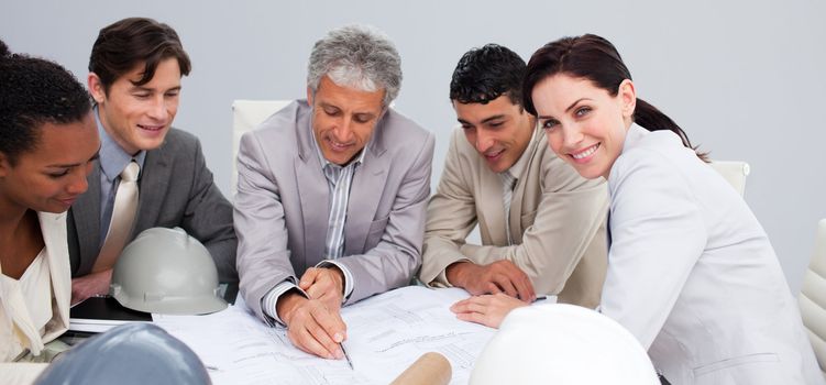 Beautiful female architect studying plans with her colleagues in a meeting