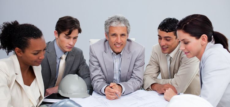 Smiling architect manager in a meeting with his team studying plans