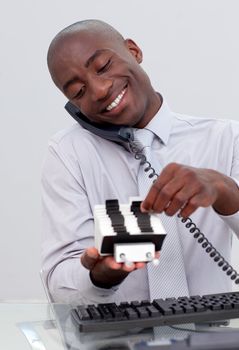 Afro-American businessman on phone and looking at an index holder