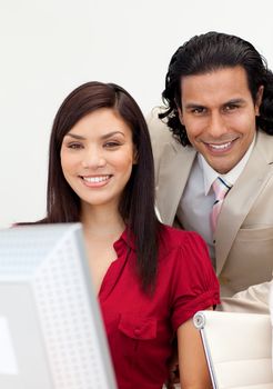 Man and woman working together smiling at the camera in the office