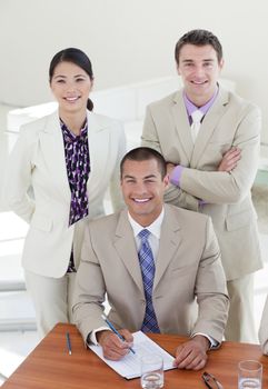 Young confident manager and his team smiling at the camera in the office