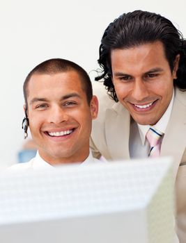 Smiling businessman helping his colleague at a computer in the office