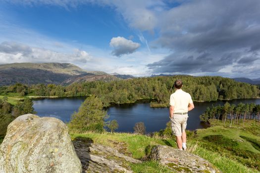 Senior hiker looks over Tarn Hows in English Lake District