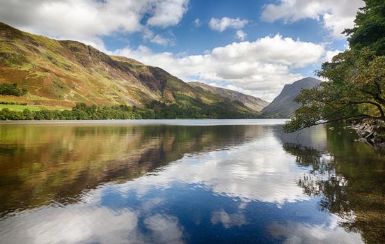 Mountains reflect into Buttermere calm lake in English Lake District