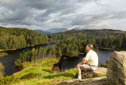Senior hiker looks over Tarn Hows in English Lake District