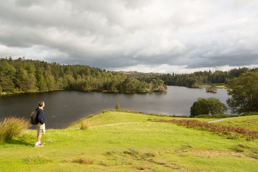 Senior hiker looks over Tarn Hows in English Lake District