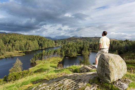 Senior hiker looks over Tarn Hows in English Lake District