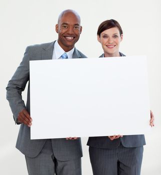 Smiling business people holding white card against white background