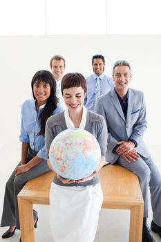 Positive international business people holding a terrestrial globe in the office 