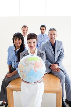 Confident business people holding a terrestrial globe in the office