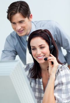 Smiling businessman helping his colleague at a computer 