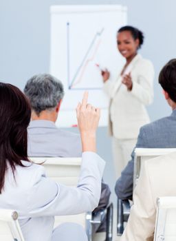 Young businesswoman asking a question at a conference with her colleagues