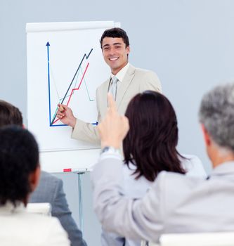 Mature businessman asking a question at a conference with his colleagues