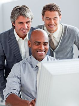 Positive businessmen helping their colleague at a computer in the office