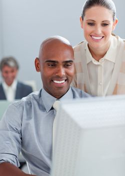 Confident businesswoman helping her colleague at a computer in the office