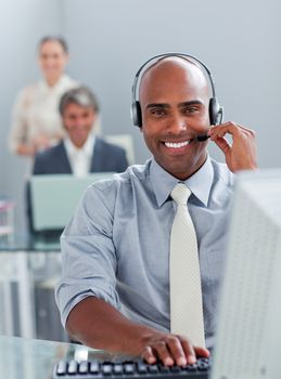 Ethnic businessman working at a computer with headset on in the office