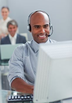 Smiling businessman with headset on working at a computer in the office