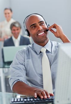 Cheerful businessman working at a computer with headset on in the office