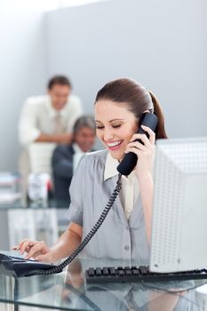 Smiling businesswoman on phone at her desk in the office