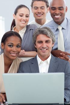 A business group showing ethnic diversity working at a laptop in the office