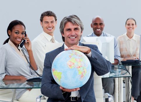 Fortunate business team at work showing a terrestrial globe  in the office