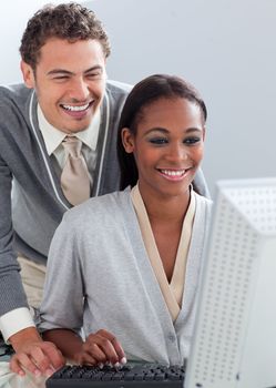 Smiling businessman helping his colleague at a computer in the office