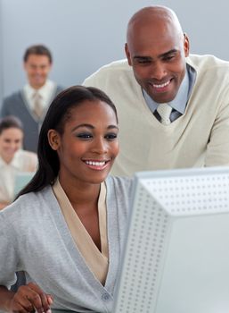 Confident businessman helping his colleague at a computer in the office