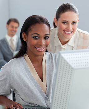 Charismatic businesswoman helping her colleague at a computer in the office