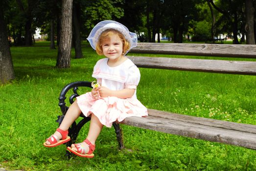 Little girl sitting on the bench in park