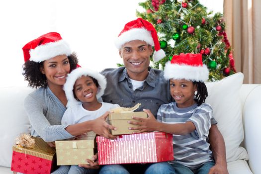 Smiling Afro-American family sharing Christmas presents on the sofa