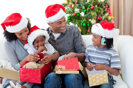 Happy Afro-American family opening Christmas presents at home